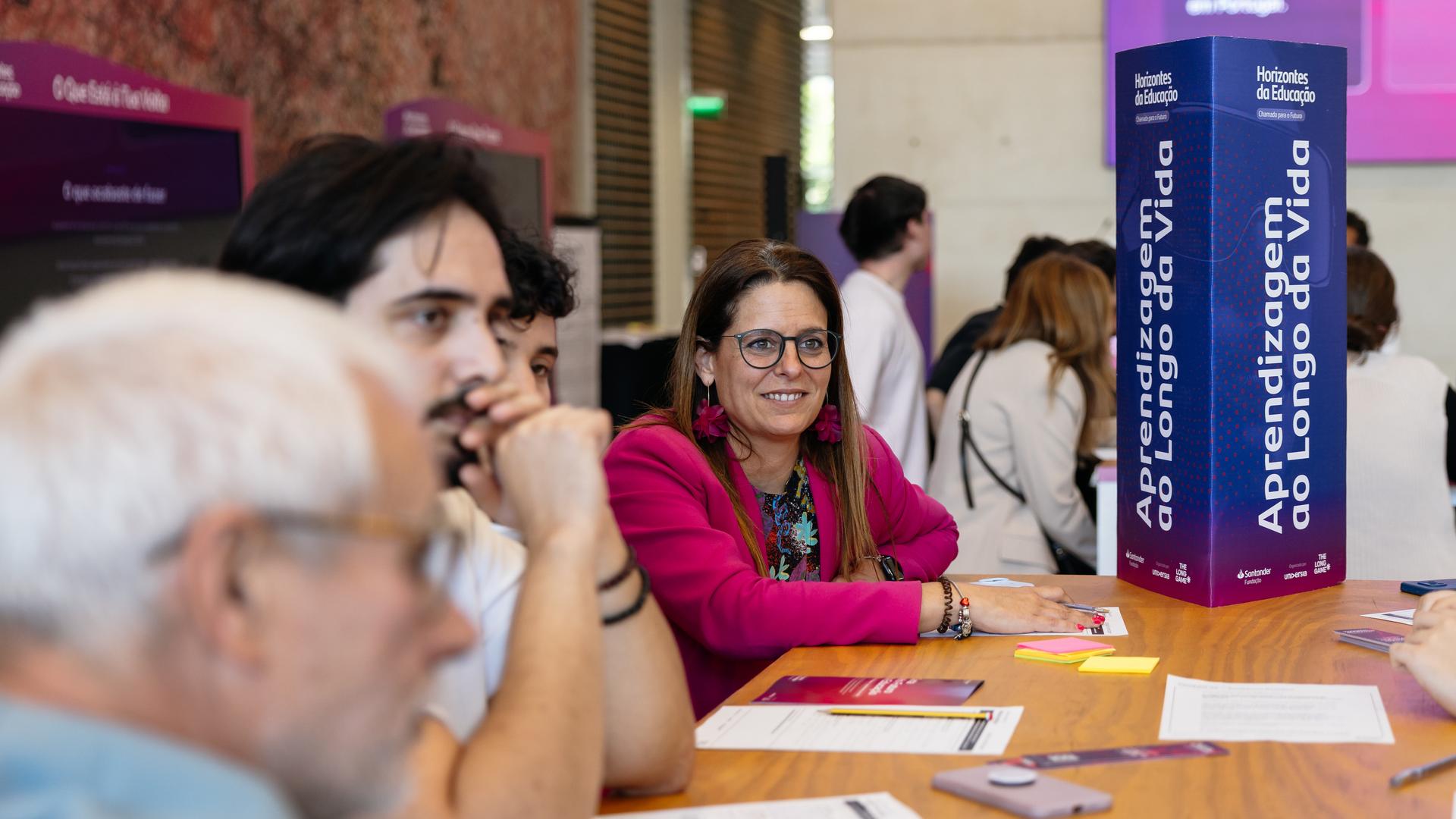 Participante numa sessão dos Horizontes da Educação, à mesa de trabalho, junto ao totem «Aprendizagem ao Longo da Vida»